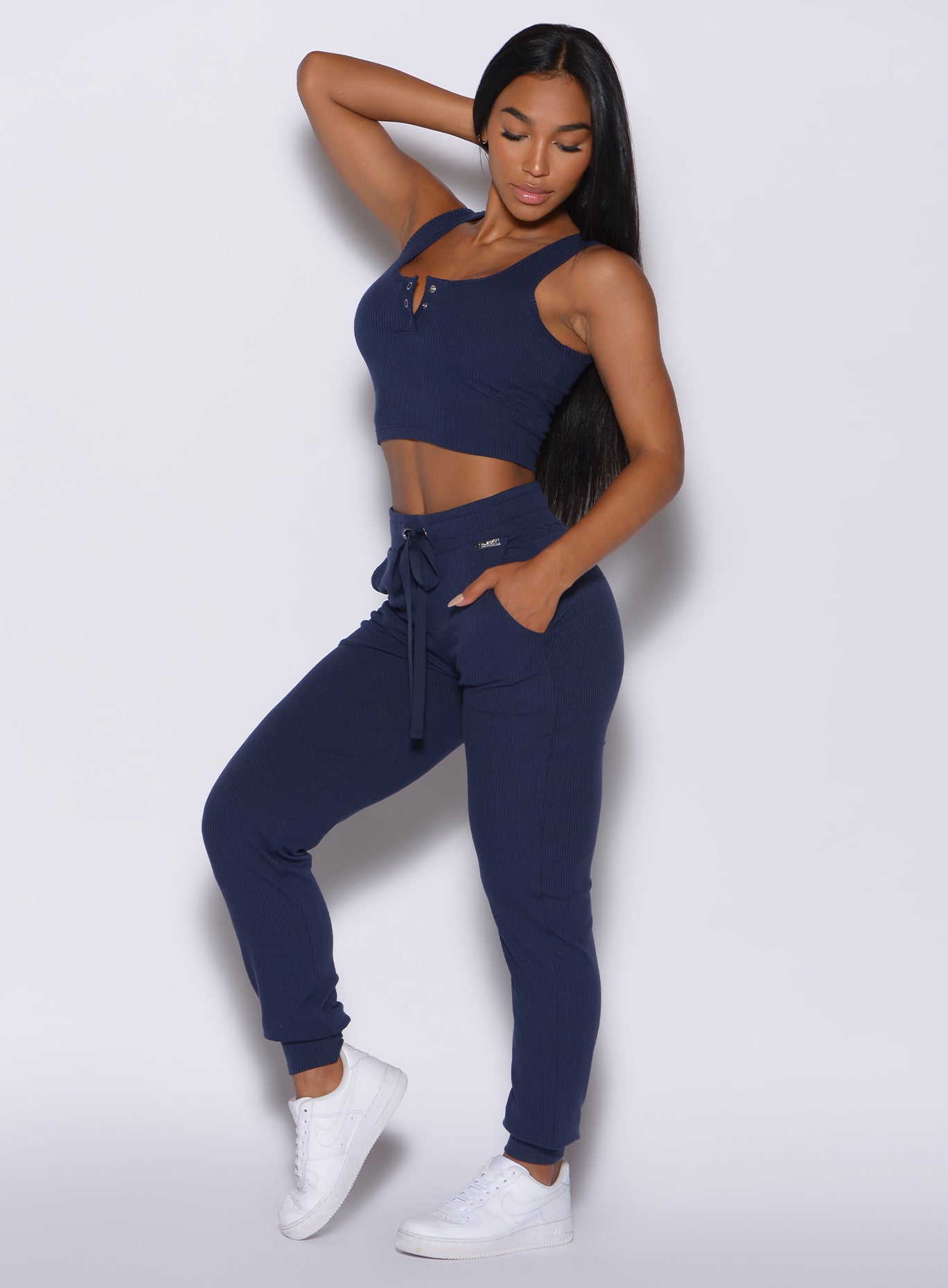 left side profile view of a model angled left wearing  our comfort rib joggers in navy and a matching bra