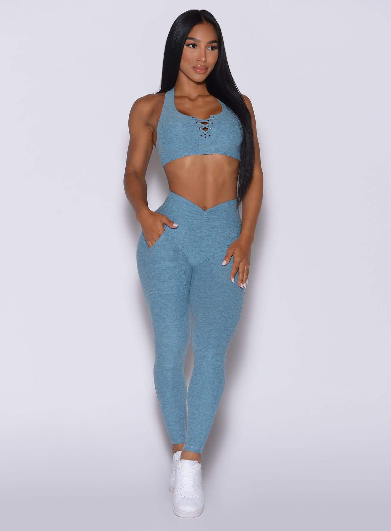 Front profile view of a model wearing our V scrunch leggings in baby blue color and a matching bra