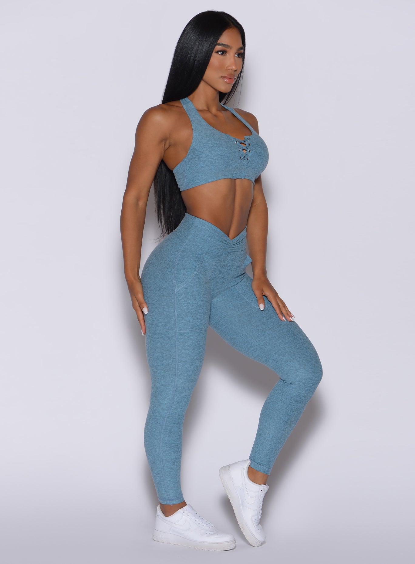 Right side profile view of a model angled to her right wearing our V scrunch leggings in baby blue color and a matching bra 