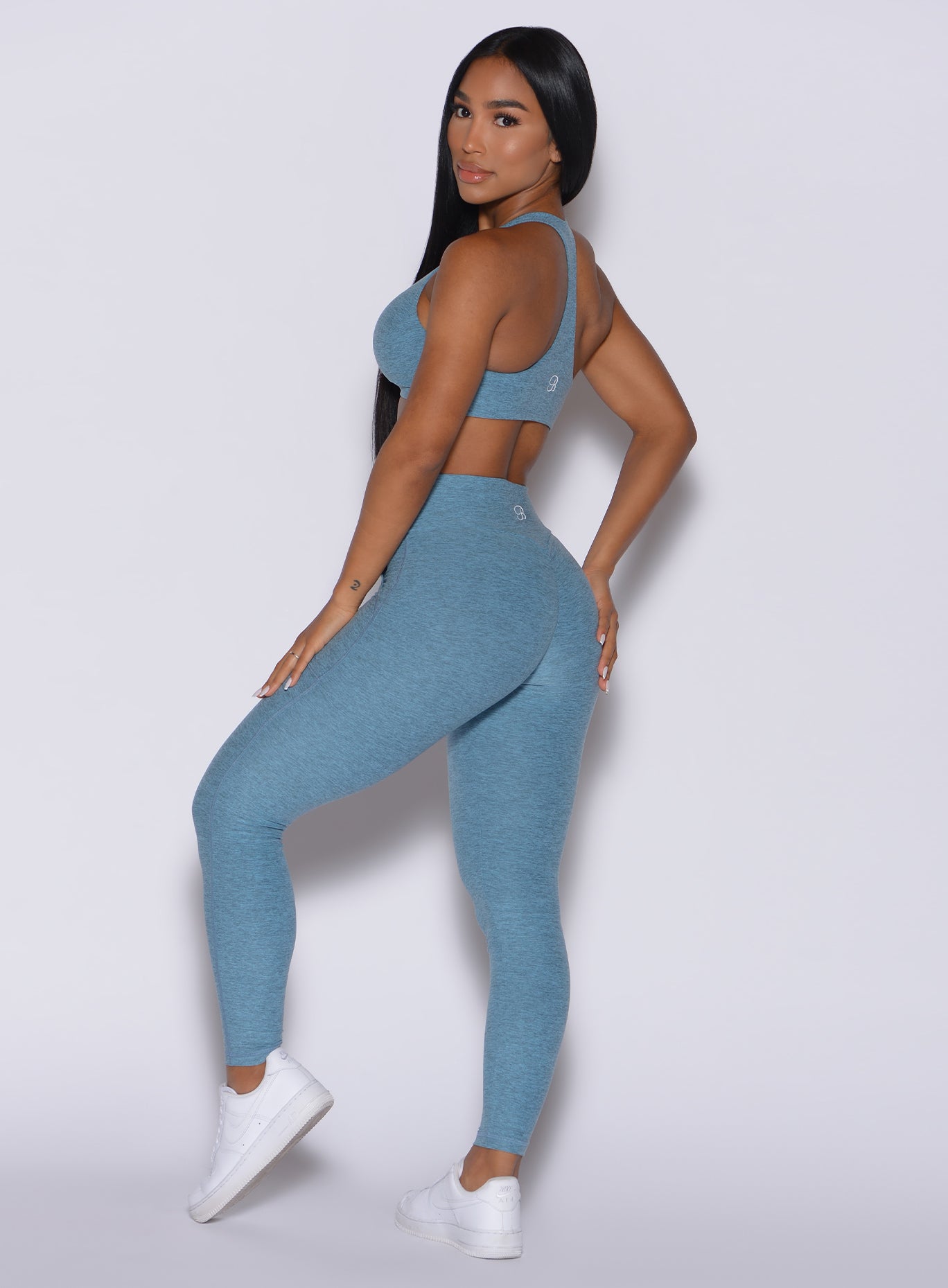 Left side  profile view of a model facing to her left wearing our our V scrunch leggings in babyblue color and a matching bra