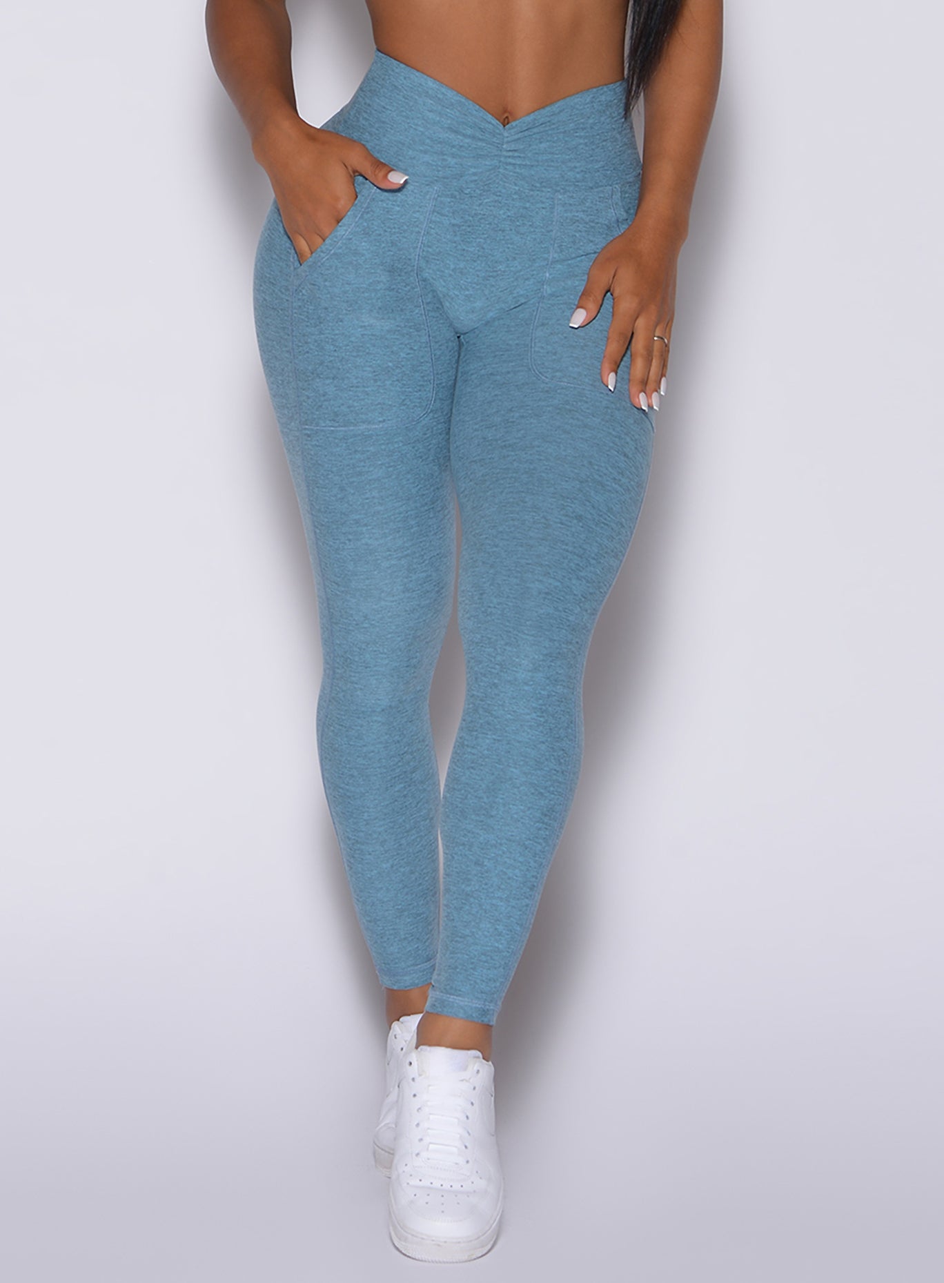 Zoomed in front profile view of a model wearing our V scrunch leggings in baby blue color 