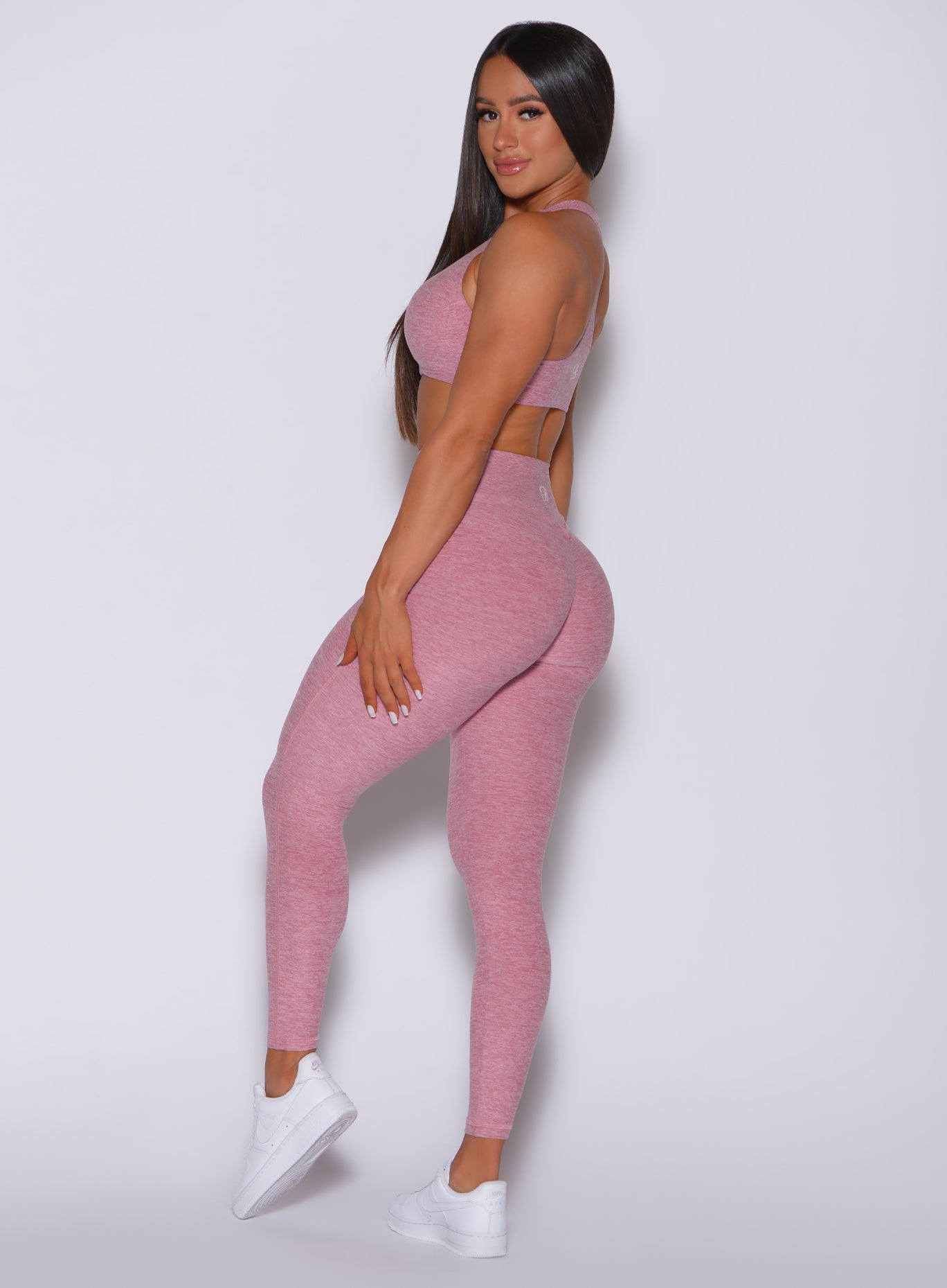 Left side profile view of a model facing to her left wearing our V scrunch leggings in rose blush color and a matching bra