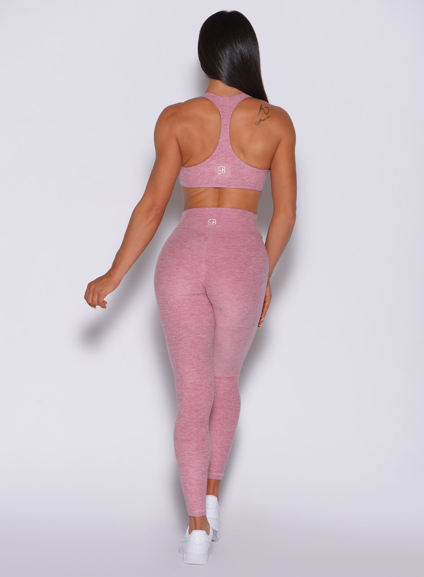 Back profile view of a model wearing our V scrunch leggings in rose blush color and a matching sports bra