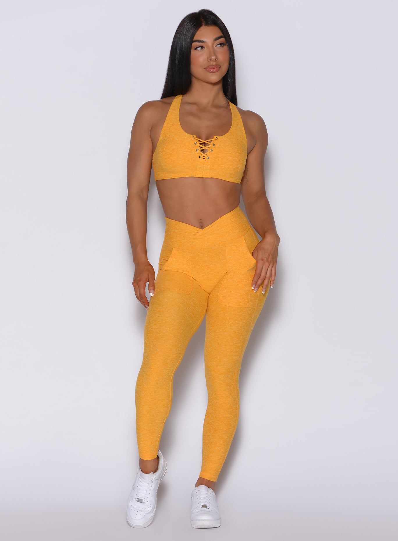 Front  profile view of a model wearing our V scrunch leggings in sinkissed color and a matching bra