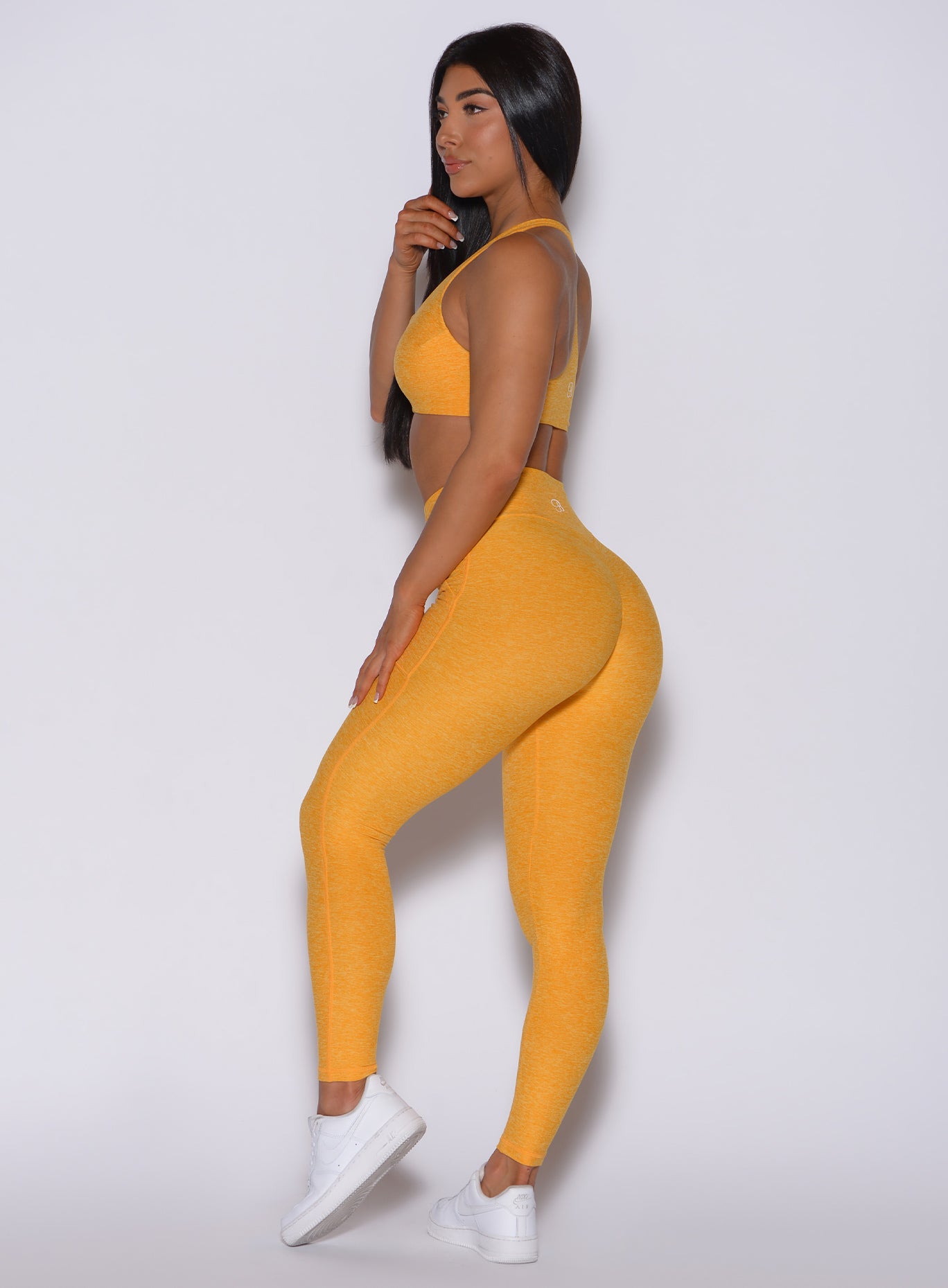 Left side  profile view of a model in our V scrunch leggings in sinkissed color and a matching sports bra