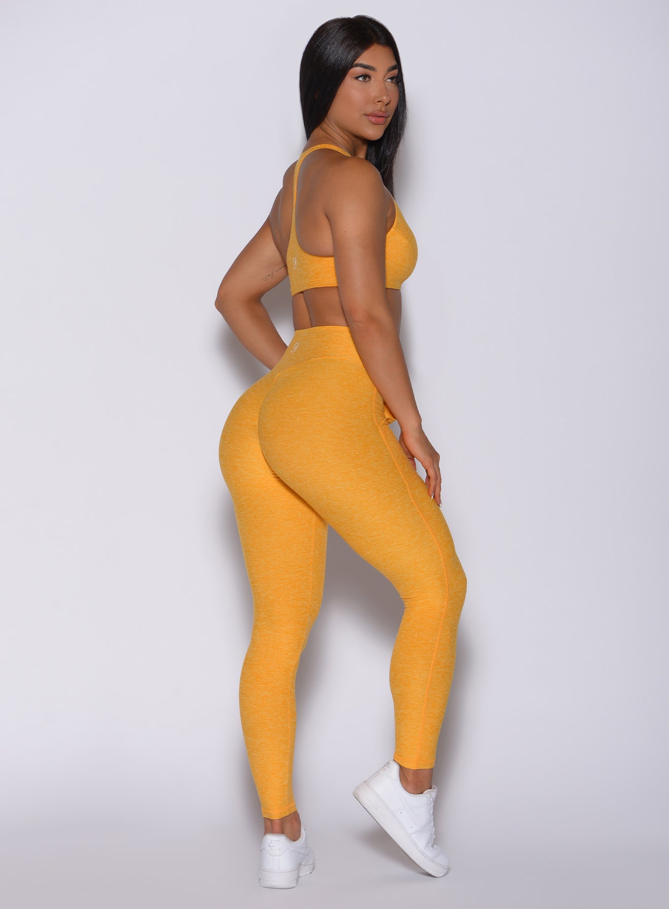 Right side profile view of a model in our V scrunch leggings in sinkissed color and a matching bra 