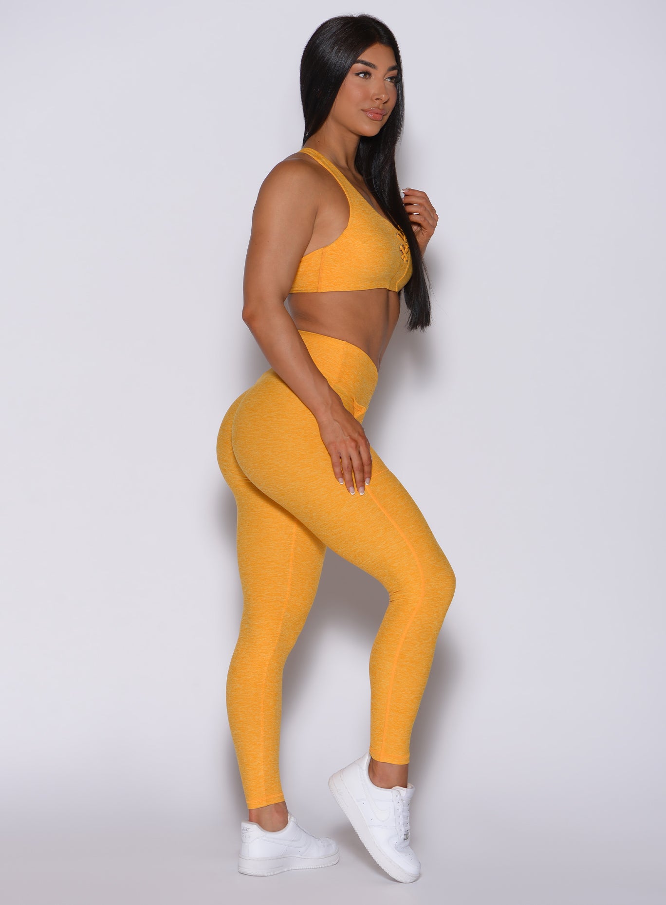 Right side  profile view of a model wearing our V scrunch leggings in sinkissed color and a matching bra