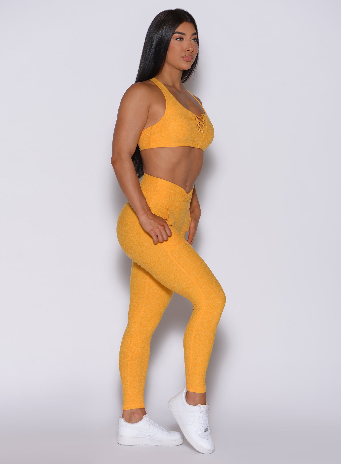 Right side profile view of a model in our V scrunch leggings in sinkissed color and a matching bra