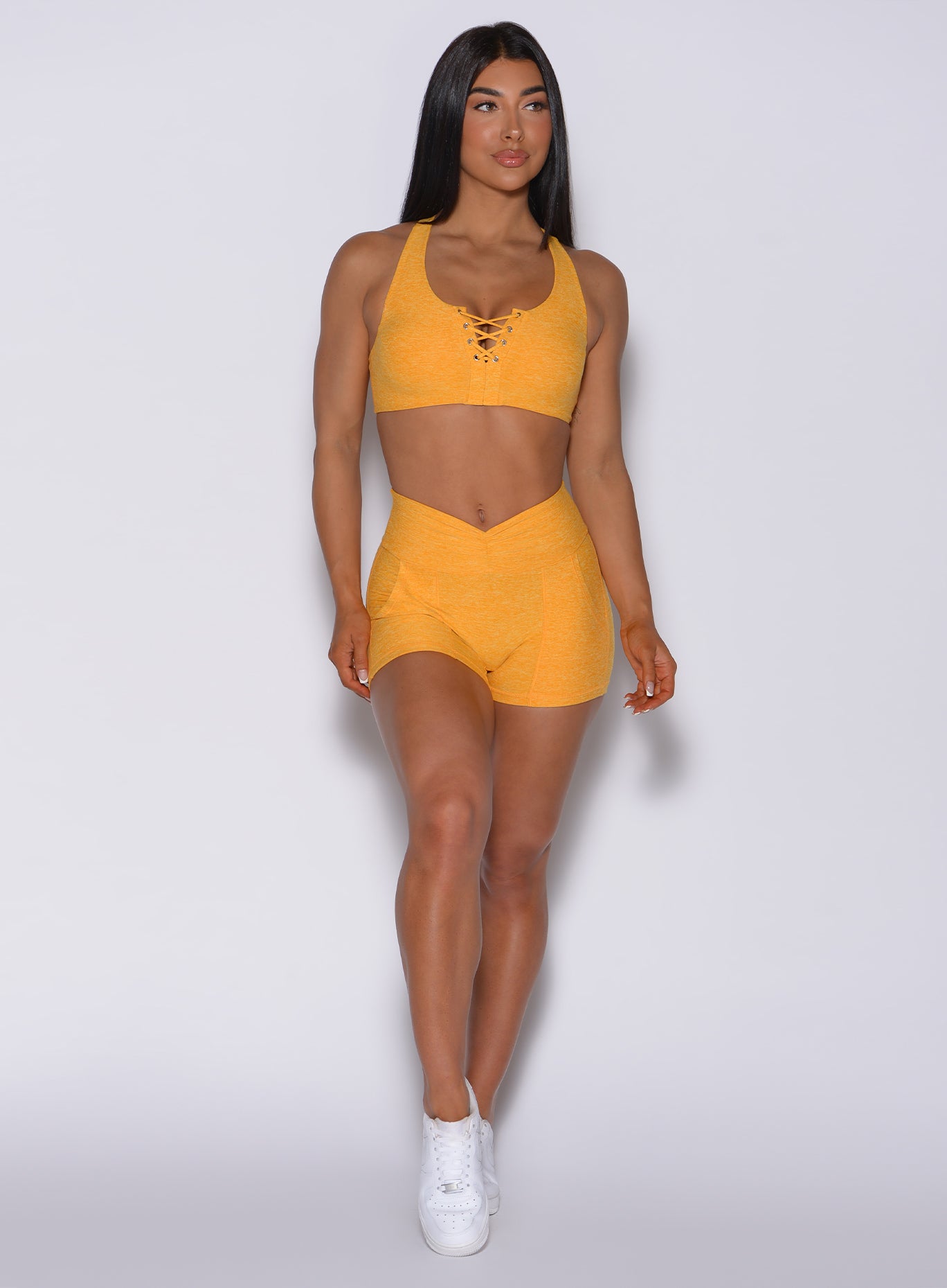 Model facing forward wearing our V scrunch shorts in sunkissed color and a matching bra