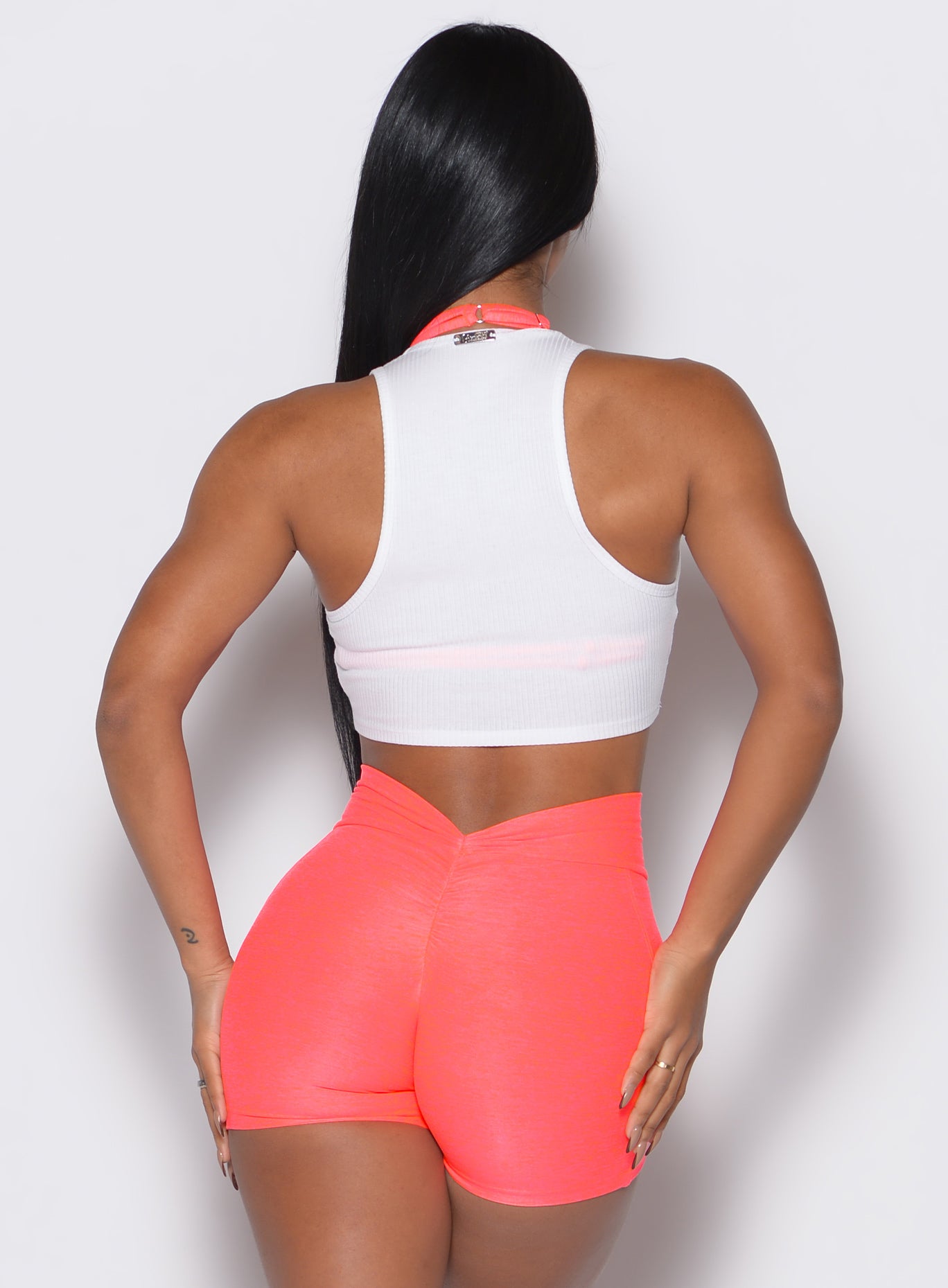 back profile view of a model wearing our white Butterfly Rib Tank on the top of a pink sports bra