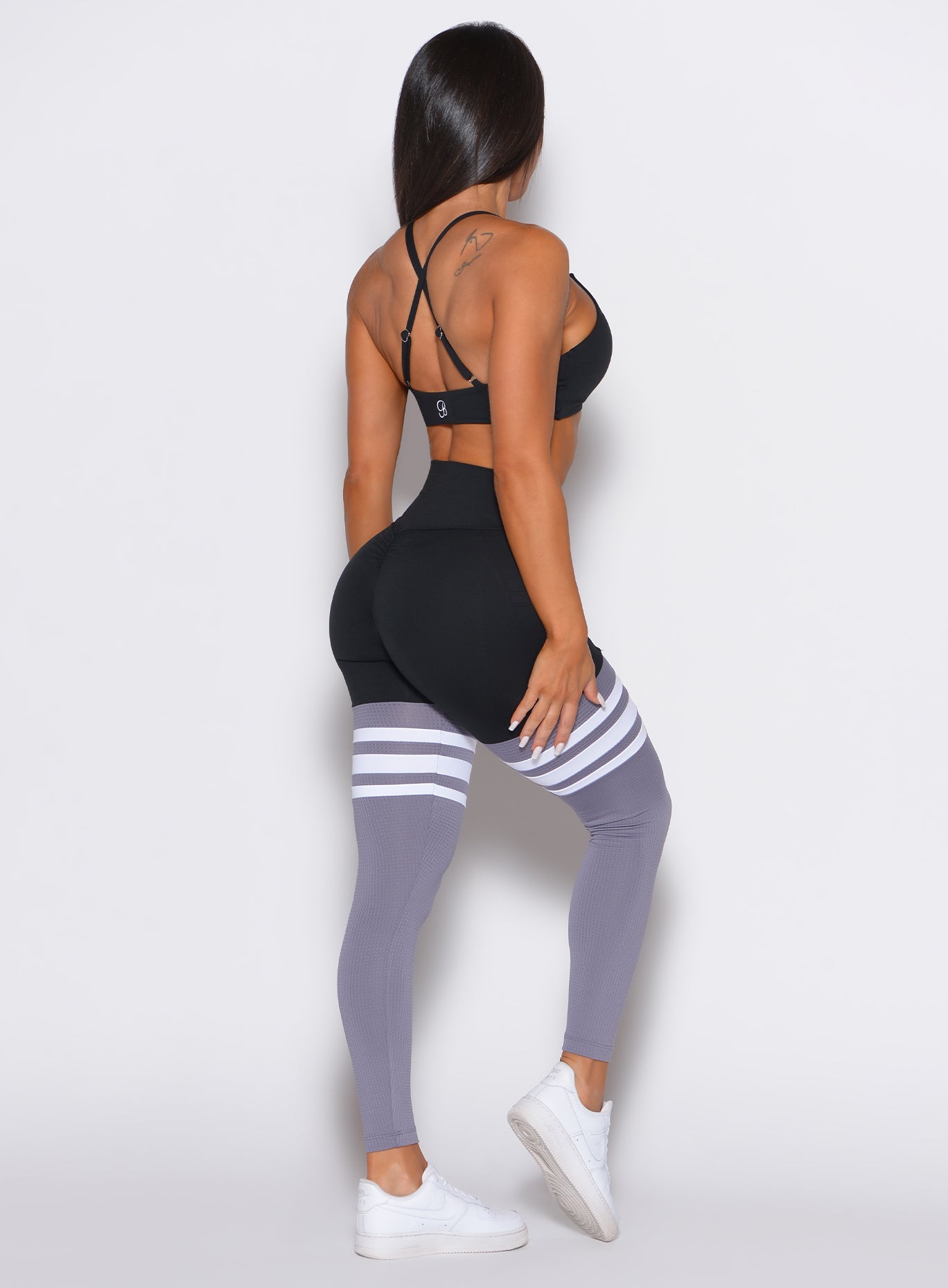 right side profile video of a model angled slightly to her left wearing our scrunch thigh high in black and gray color along with a black sports bra 