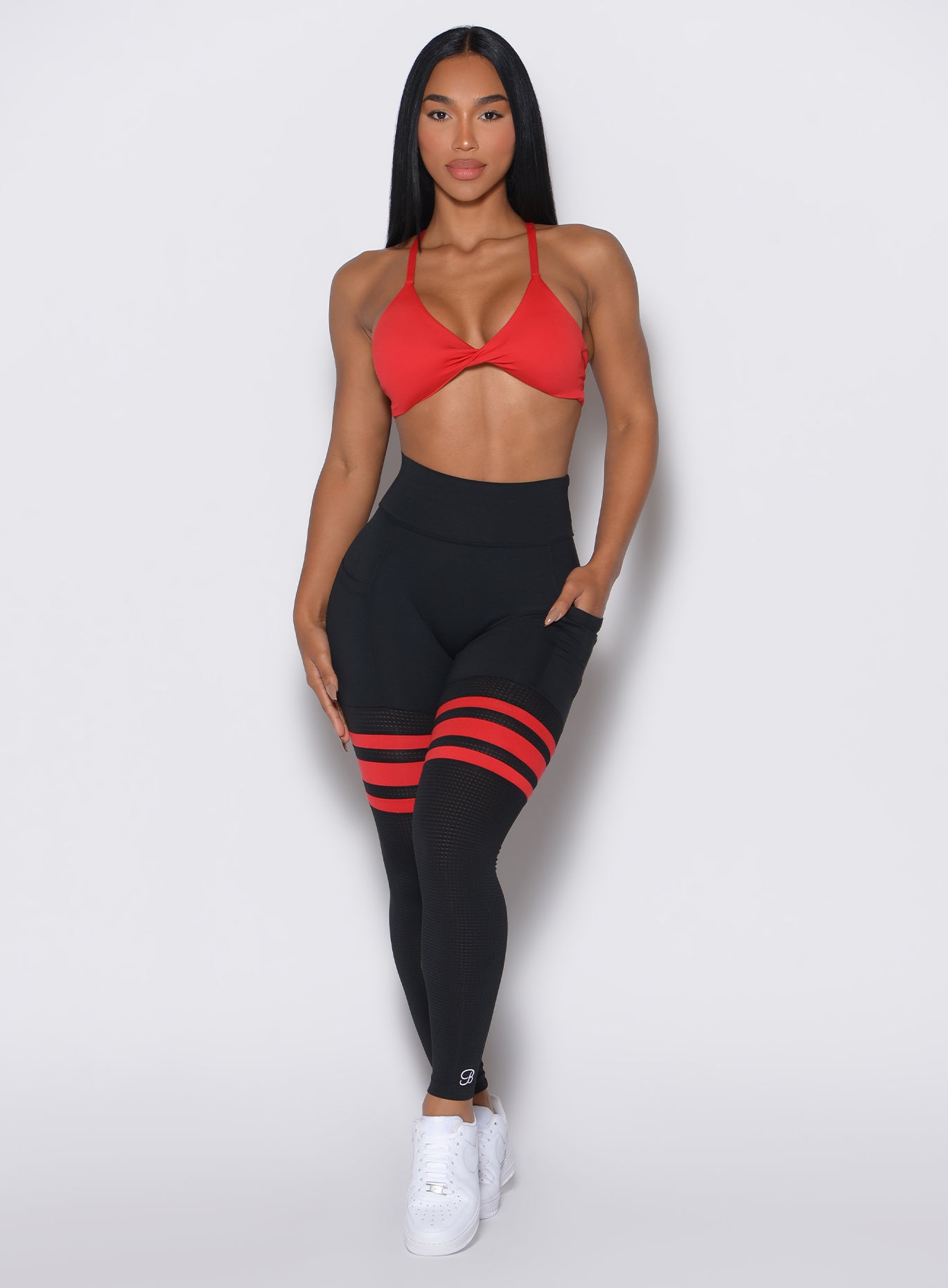 Front profile shot of a model with her left hand hand in the pocket of the leggings wearing the Scrunch Thigh Highs in Black Fire color along with the matching top