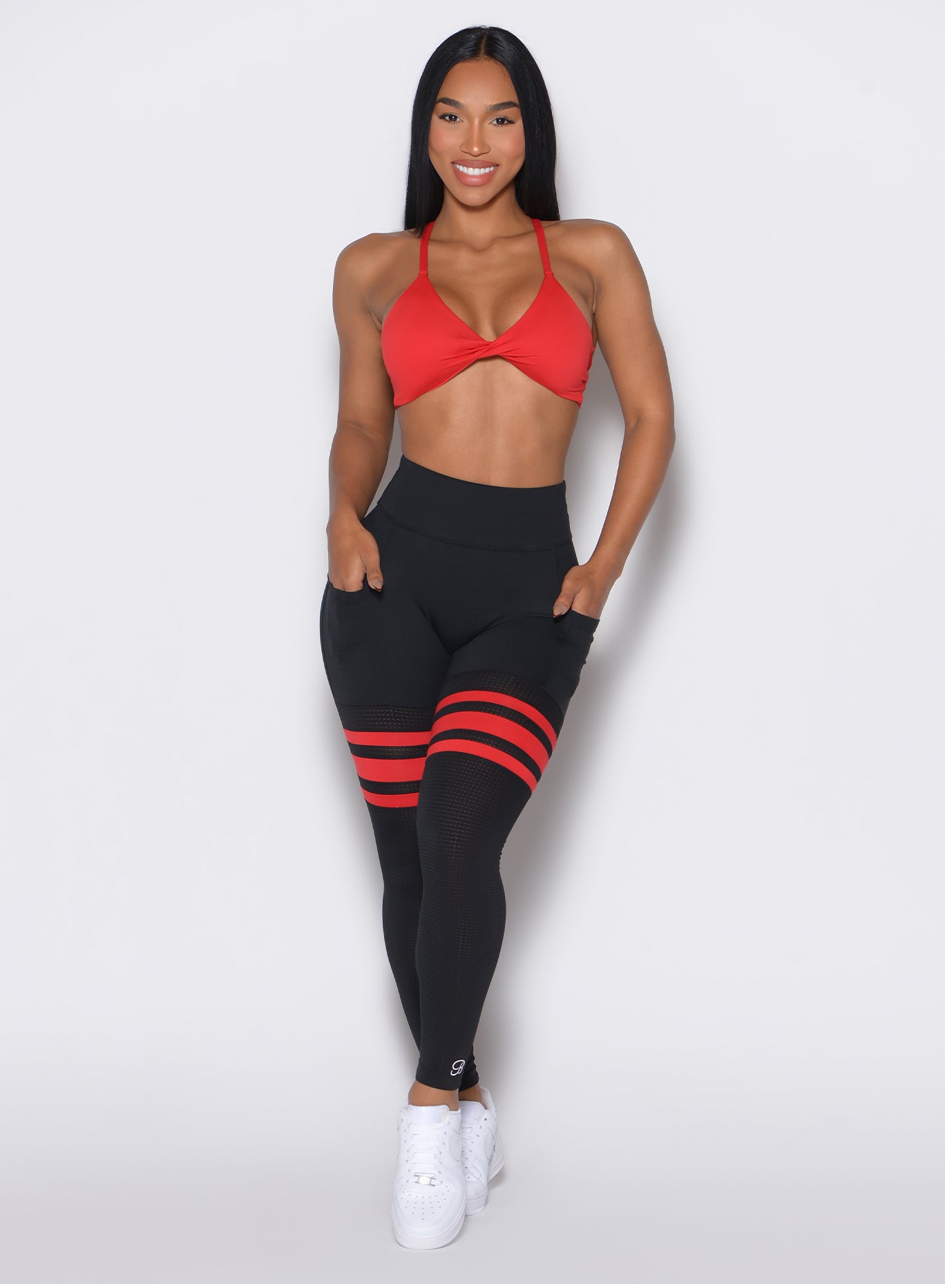 Front profile view of a model wearing the Scrunch Thigh Highs in Black Fire color along with a red sports bra