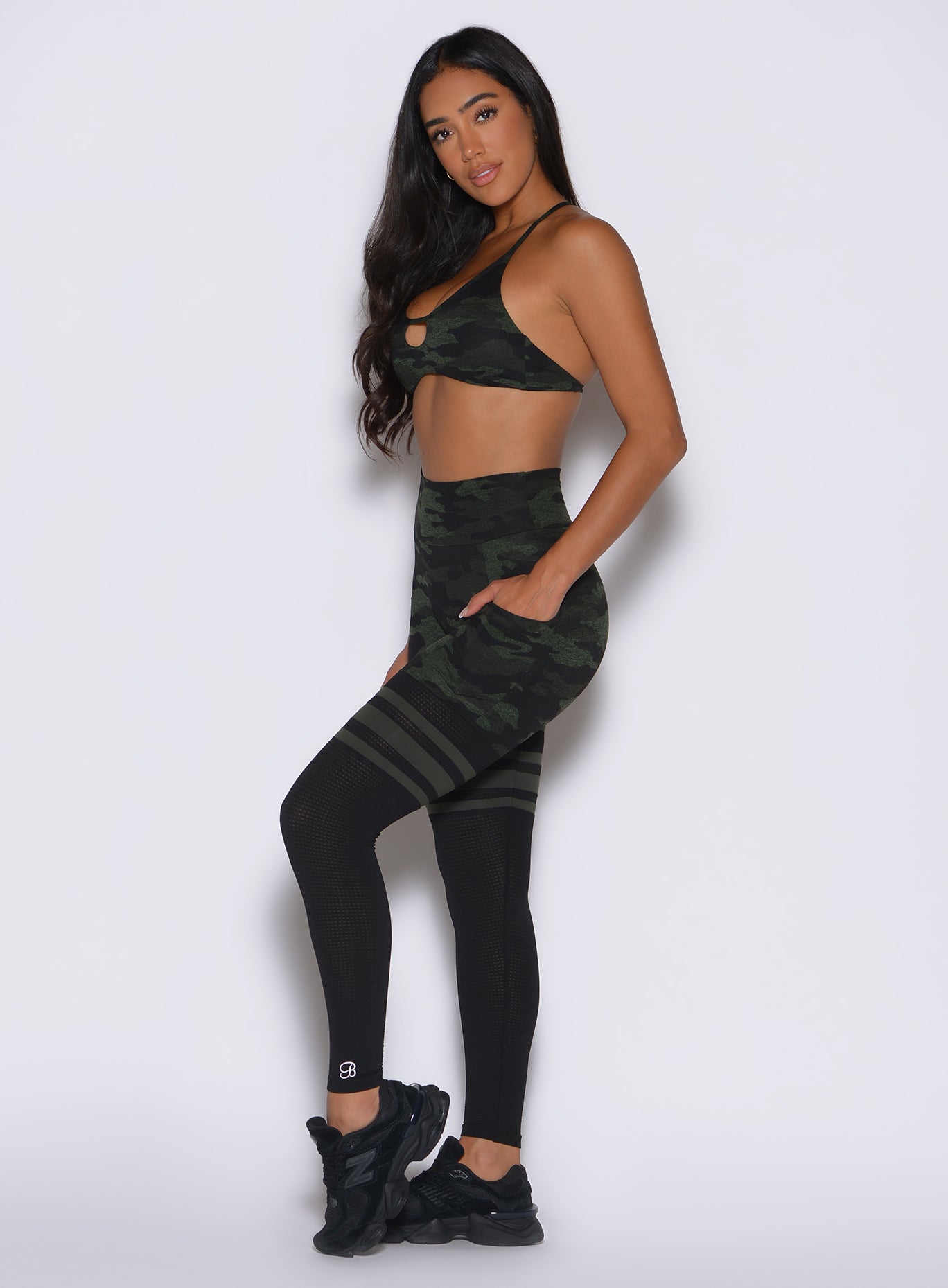 left side profile view of a model wearing the Scrunch Thigh Highs in Green/Black camo color