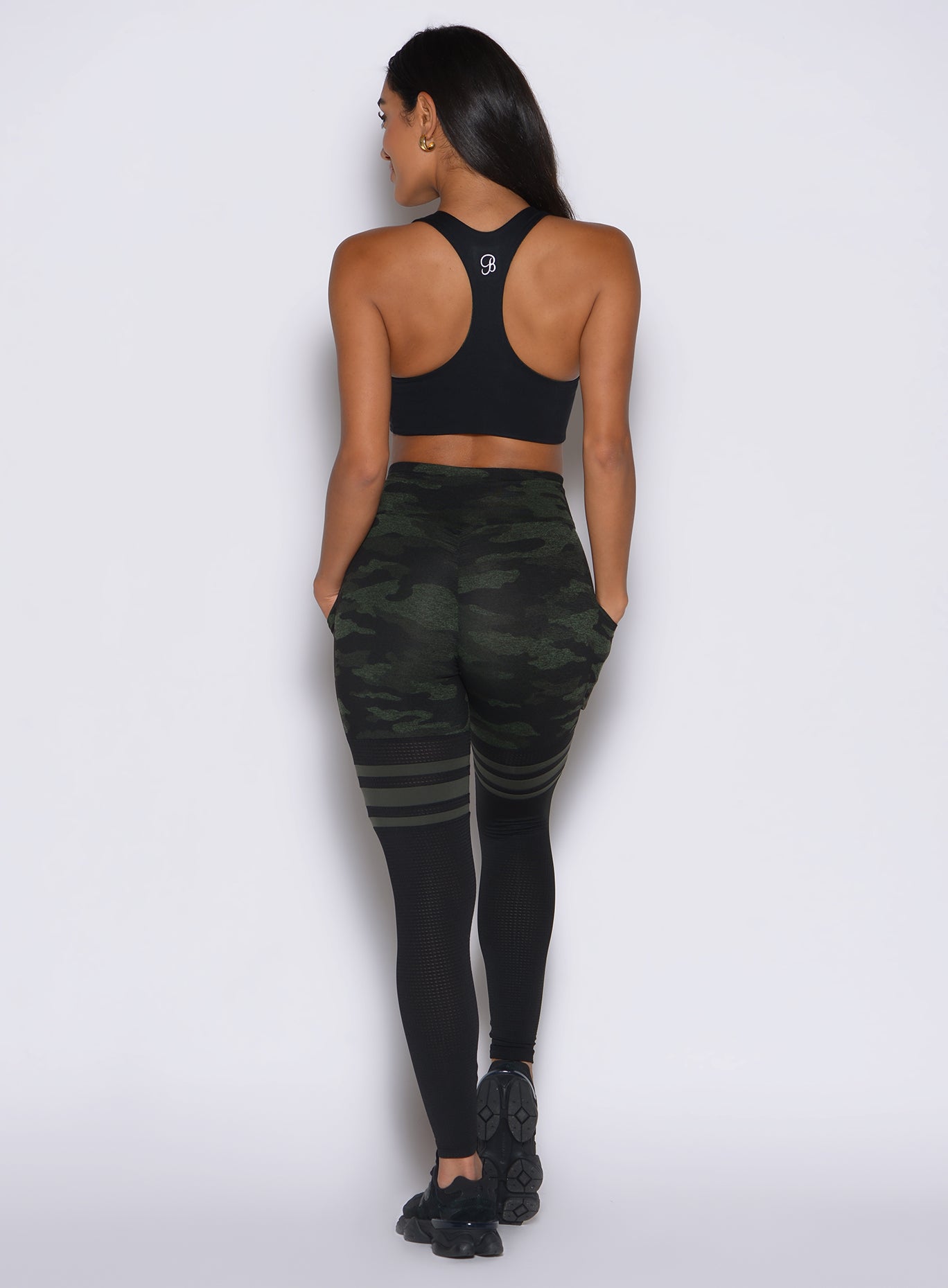 back side profile view of a model facing to the left side wearing the Scrunch Thigh Highs in Green/Black camo color
