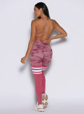 back profile view of a model with one hand on her waist and facing to the left side wearing the Scrunch Thigh Highs in Hibiscus camo color