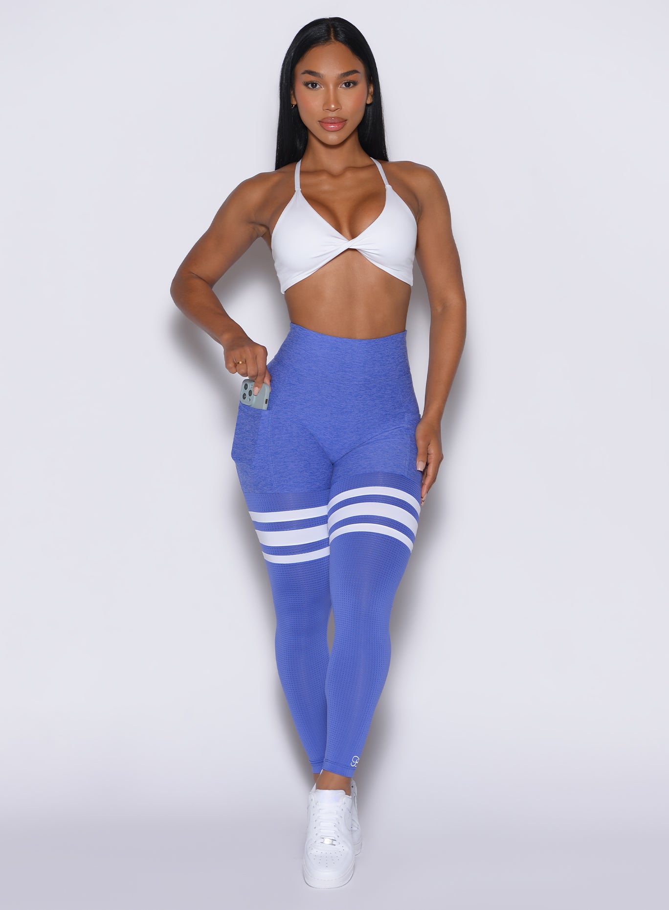front profile view of a model wearing our scrunch thigh-highs in violet blue with three white stripes on the thighs, complemented by a matching white sports bra.
