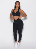 front profile view of a model holding the waistband wearing the Sculpt Knot Leggings in black color