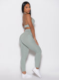 right side profile view of a model looking over her shoulder wearing the Sculpt Knot Leggings in Iceberg Green color