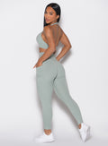 left side profile view of a model looking over her shoulder wearing the Sculpt Knot Leggings in Iceberg Green color