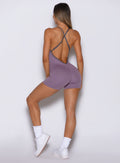 back side view of a model wearing the Lift Bodysuit Shorts in Violet frost color