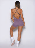 model captured from the back side wearing the Lift Bodysuit Shorts in Violet frost color