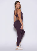 right side profile view of a model wearing the Sculptura Bodysuit in plum noir color