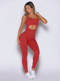 front view of a model facing to the right side wearing the Sculptura Bodysuit in Sunrise red color