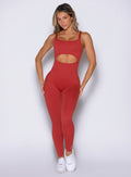 front view of a model with both hands on her thighs wearing the Sculptura Bodysuit in Sunrise red color