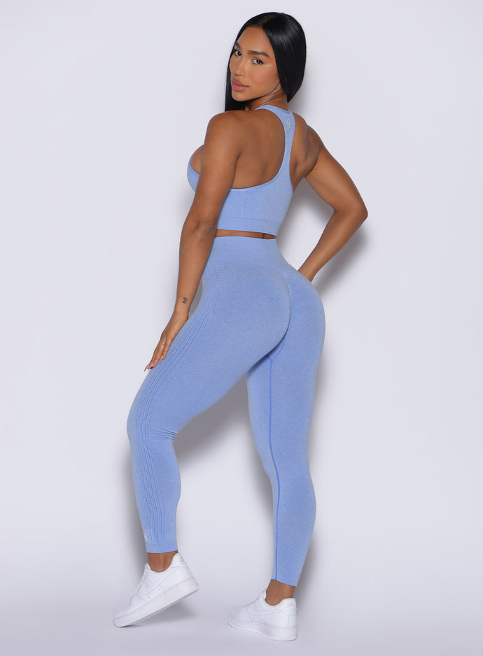 left side view of a model facing to her left wearing our Contour Seamless Leggings and the matching Lifter Heather Seamless Bra in Sky color