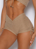 close up front view of a model wearing the Charm Fit shorts in sandstone color