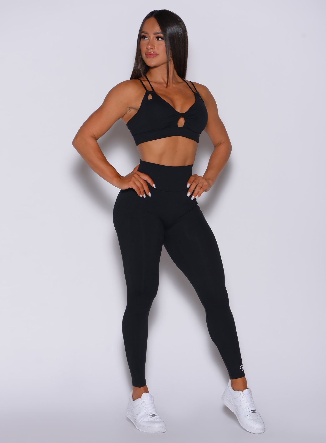 Front profile view of a model wearing our new and enhanced black shape leggings and a matching sports bra