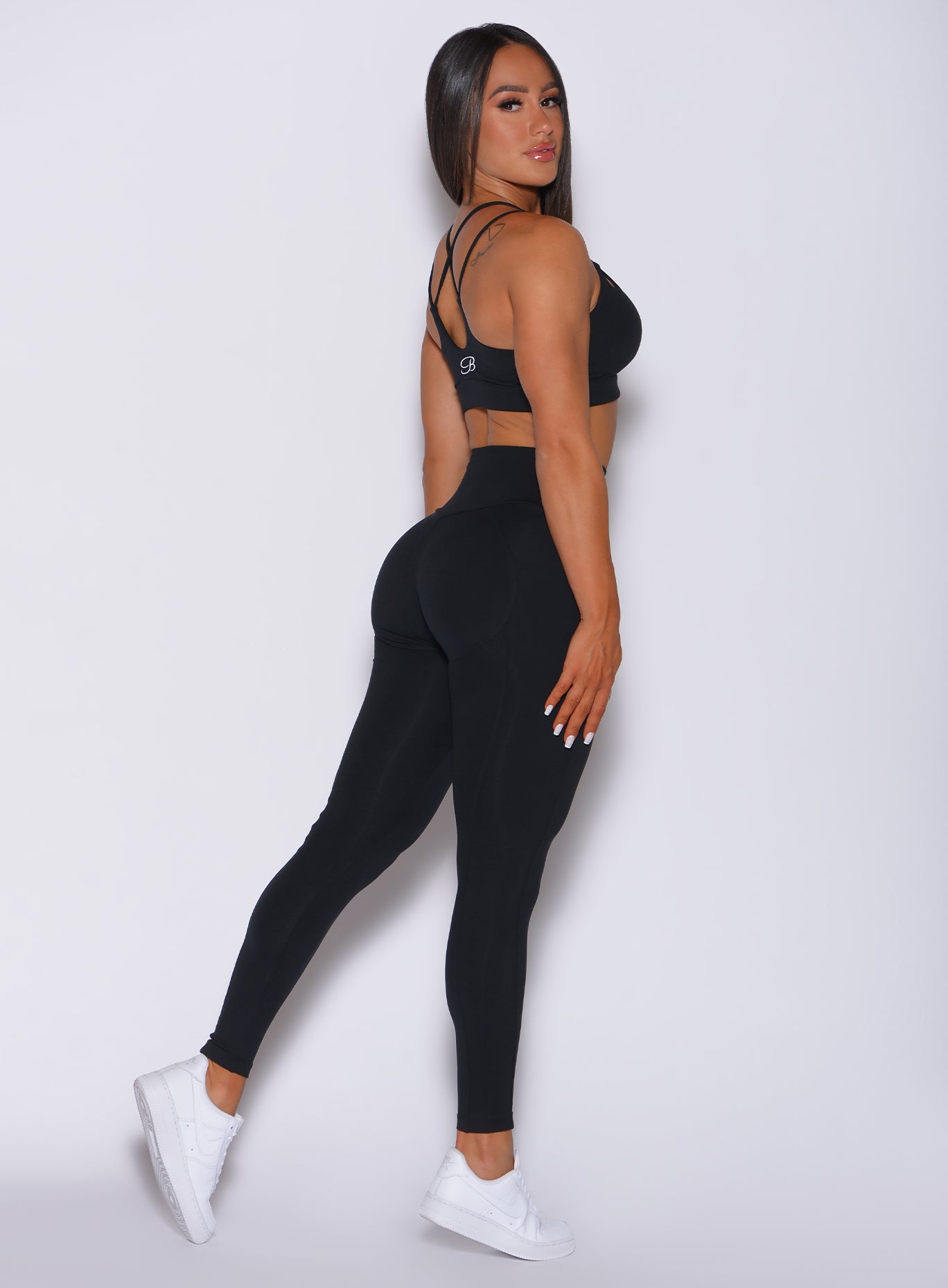Right side profile view of a model in our new and enhanced black shape leggings and a matching bra