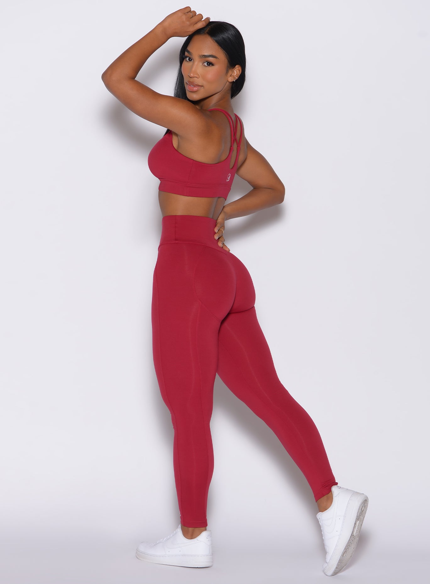 Left side profile view of a model wearing our shape leggings in maroon color along with the matching bra