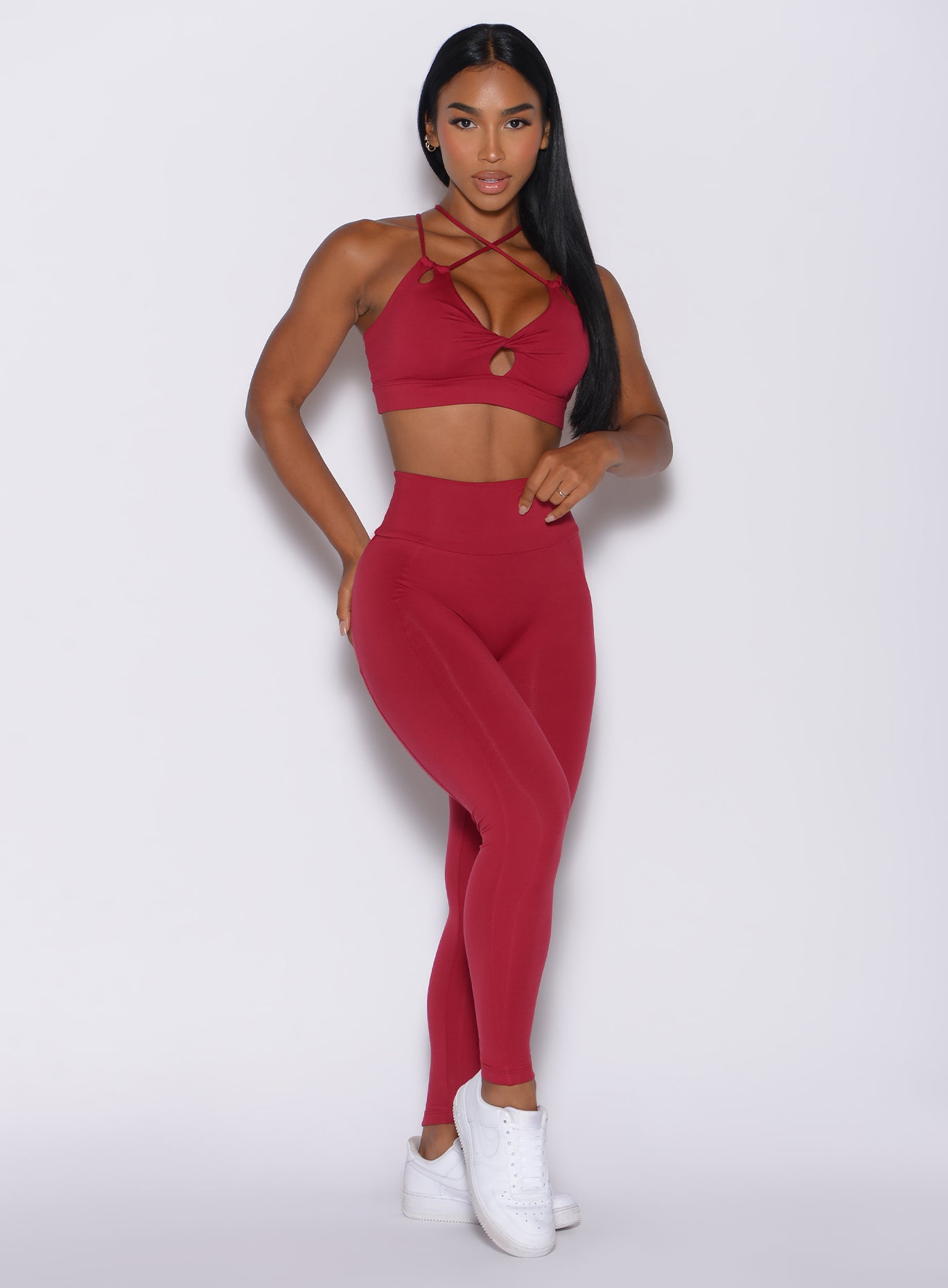 Front profile view of a model wearing our shape leggings in maroon color along with the matching bra 