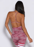back profile view of a model with one hand inside the side pocket of the leggings wearing the She owns it Bra in hibiscus camo