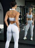 Back profile view of a model at the gym infront of a mirror wearing the Shimmer V Back Leggings in White star color