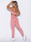 back left side profile view of a model wearing the Shimmer V Back Leggings in Pink star color paired with the matching top