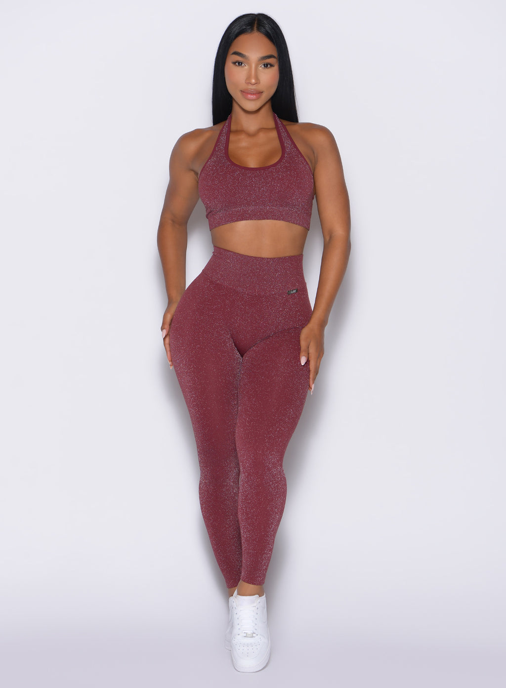 Fit model wearing a shimmery maroon sports bra with matching leggings.