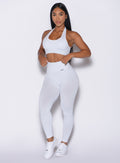 front left side profile view of a model adjusting the waistband of the leggings wearing the Shimmer V Back Leggings in White star color