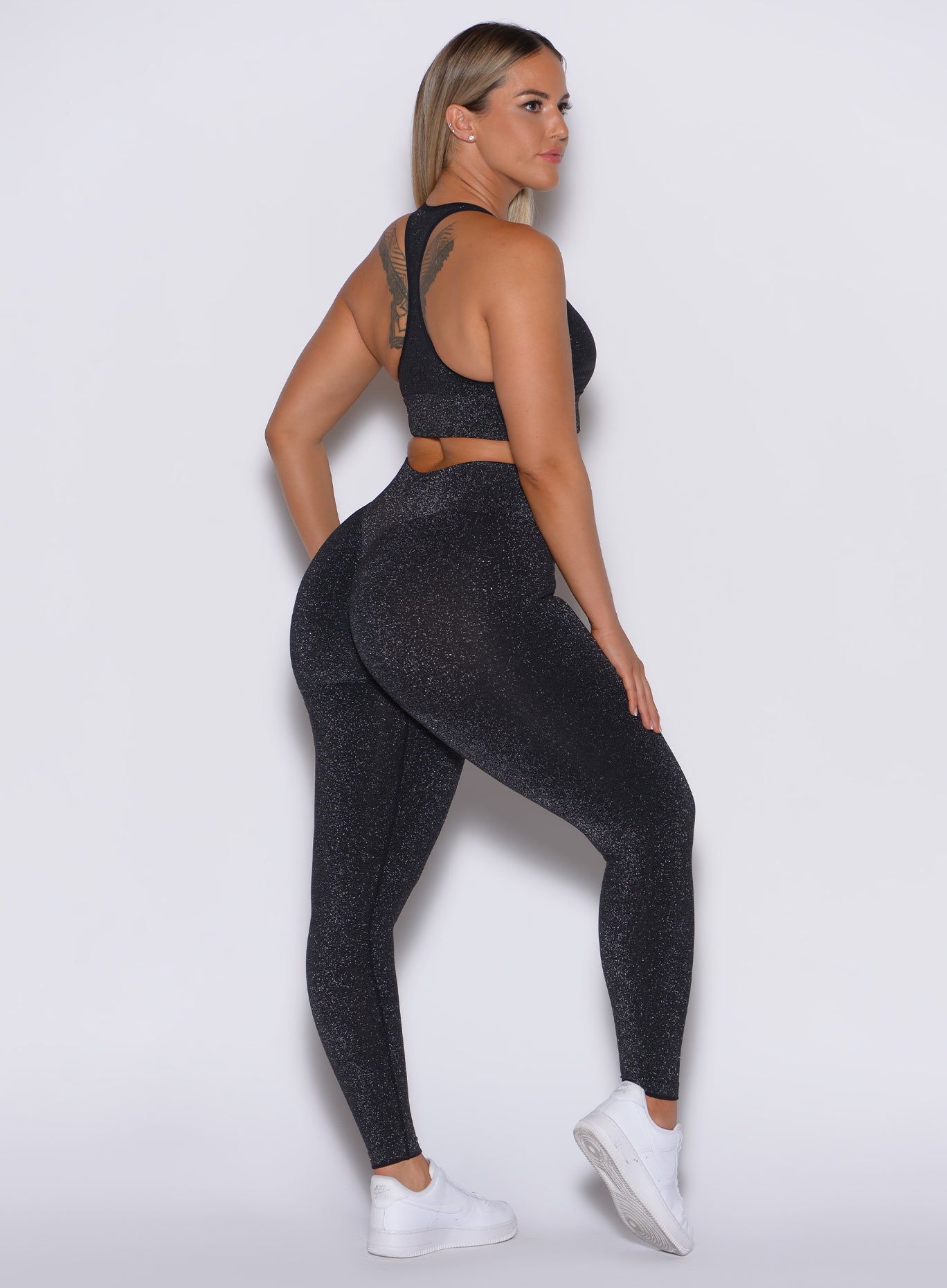 right side profile view of a model wearing our Shimmer Seamless Leggings in black sparkle color along with the matching bra