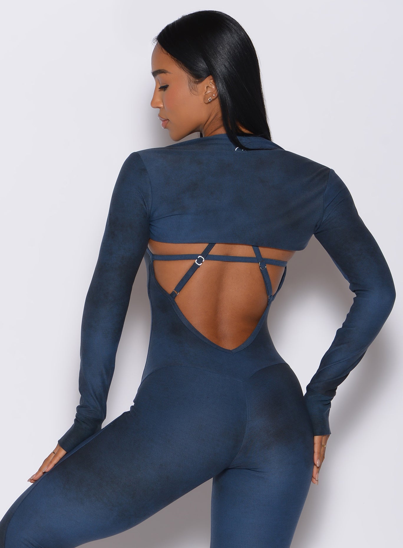 Back profile view of a model facing to her left wearing our shape shrug in vintage blue color along with the matching bodysuit