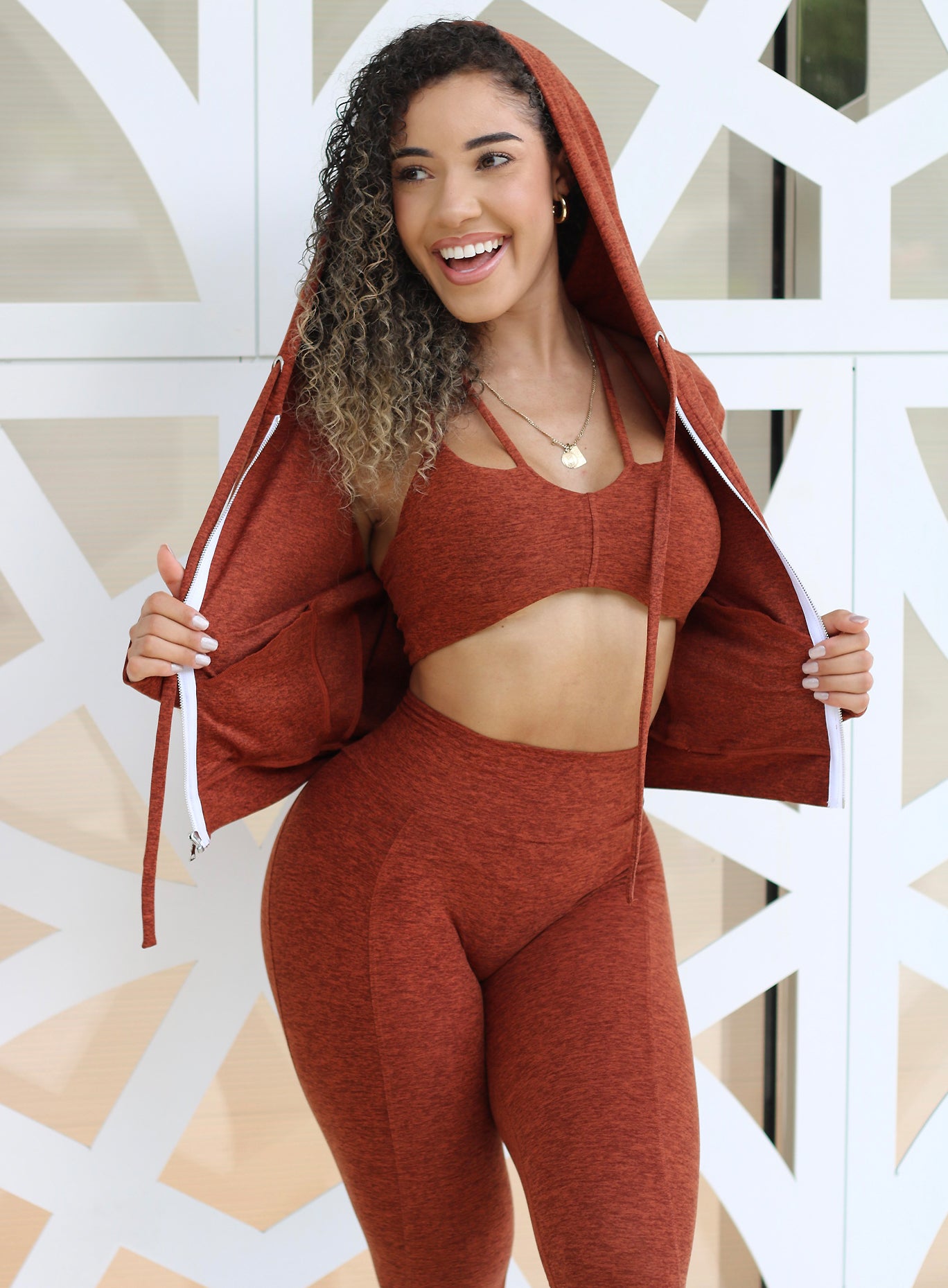 Front profile view of a model in our signature jacket in cinnamon color along with a matching bra and high waist leggings 