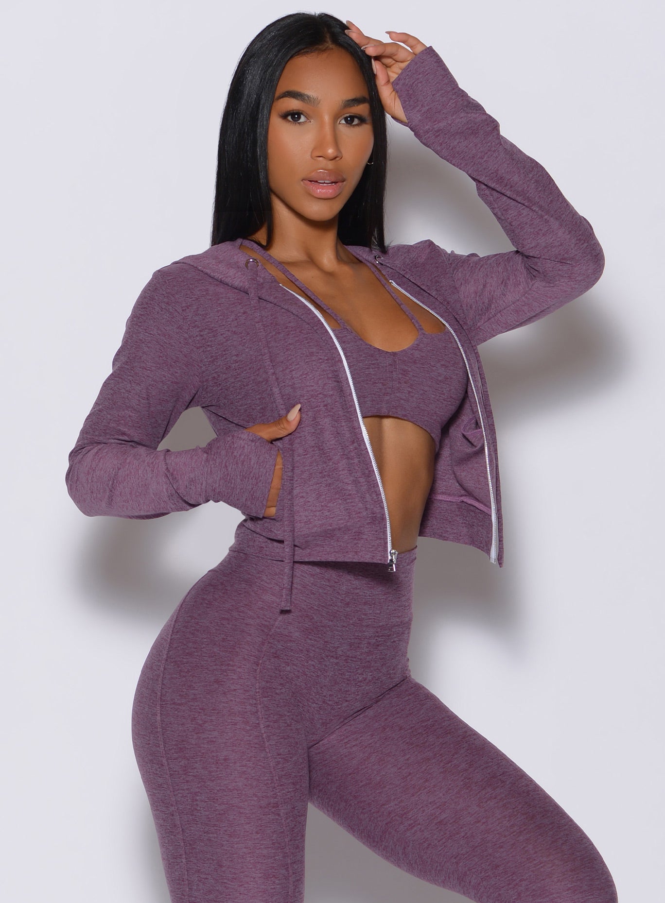 side profile view of a model facing forward wearing our signature jacket in regal purple color along with a matching leggings and bra 