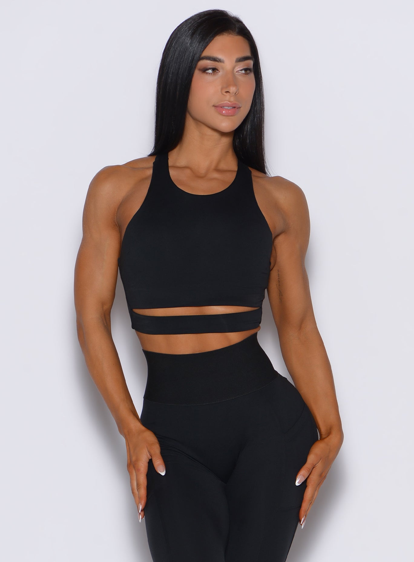 Front profile view of a model wearing our black sliced tank bra along with a matching leggings
