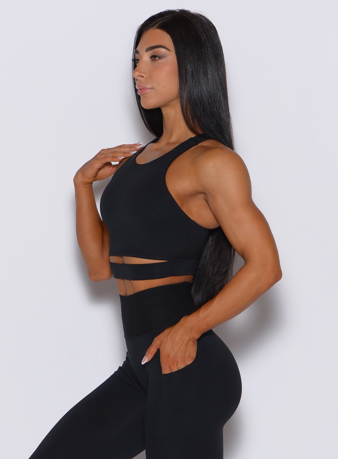 Left side profile view of a model wearing our black sliced tank bra along with a matching leggings