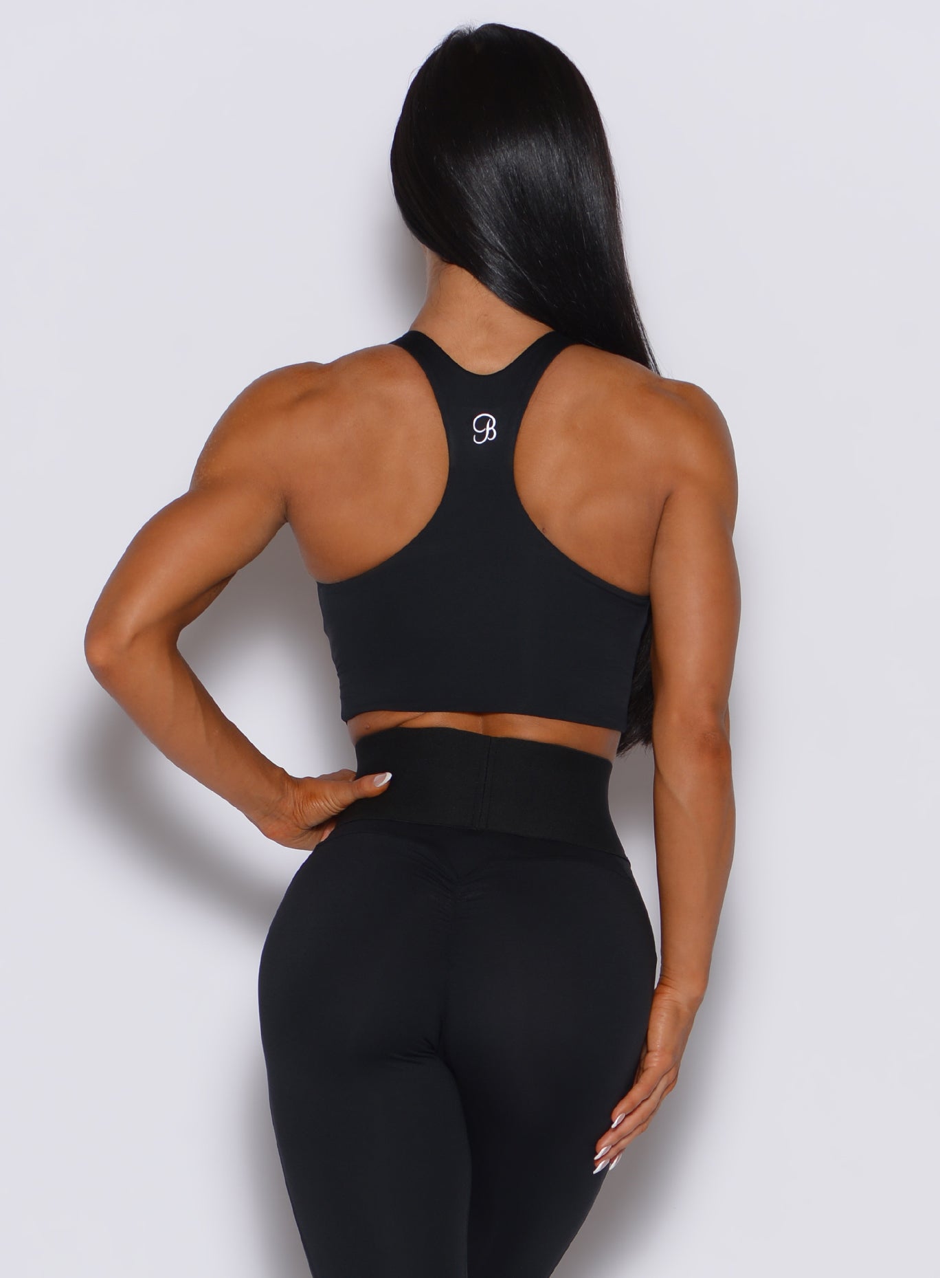 Back profile view of a model wearing our black sliced tank bra along with a matching high waist leggings