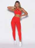 front profile view of a model wearing our Smooth Leggings and the matching bra in Cherry Bomb color