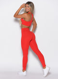 Left side view of a model wearing the Smooth Leggings and the matching bra in Cherry Bomb color