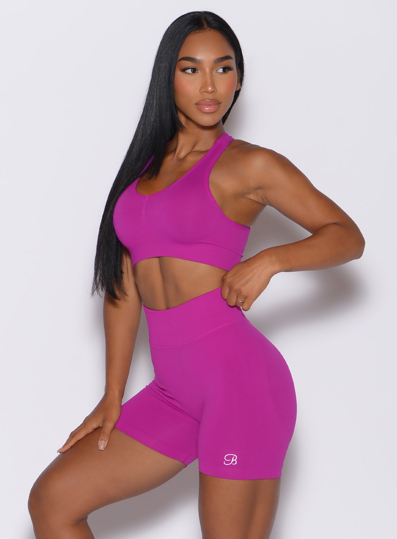 left side profile view of a model angled left wearing our smooth seamless bra in berry color along with the matching shorts